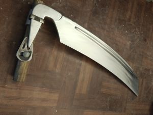 Finished machined scythe blade mounted to a handle