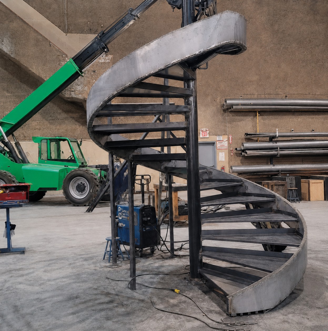 Gold spiral staircase structure being assembled in a fabrication space